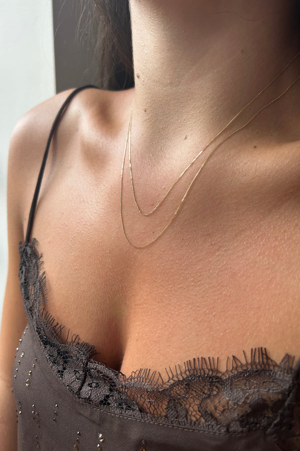 Close-up of a person wearing 2 chains to illustrate the difference in lengths