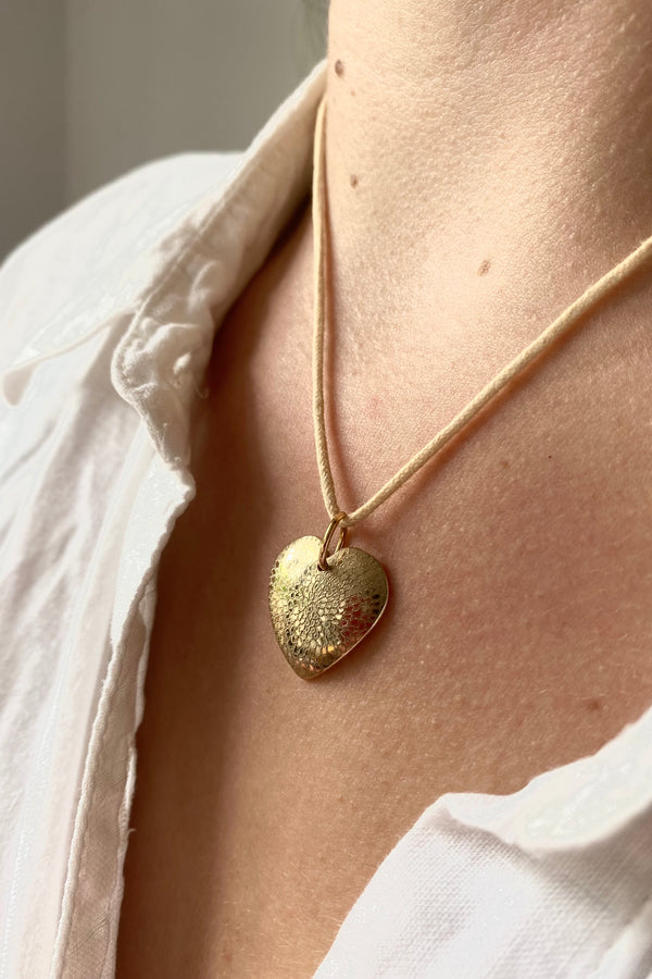 9ct yellow gold engraved pendant with a chrysanthemum design shown on a model wearing a white blouse. 