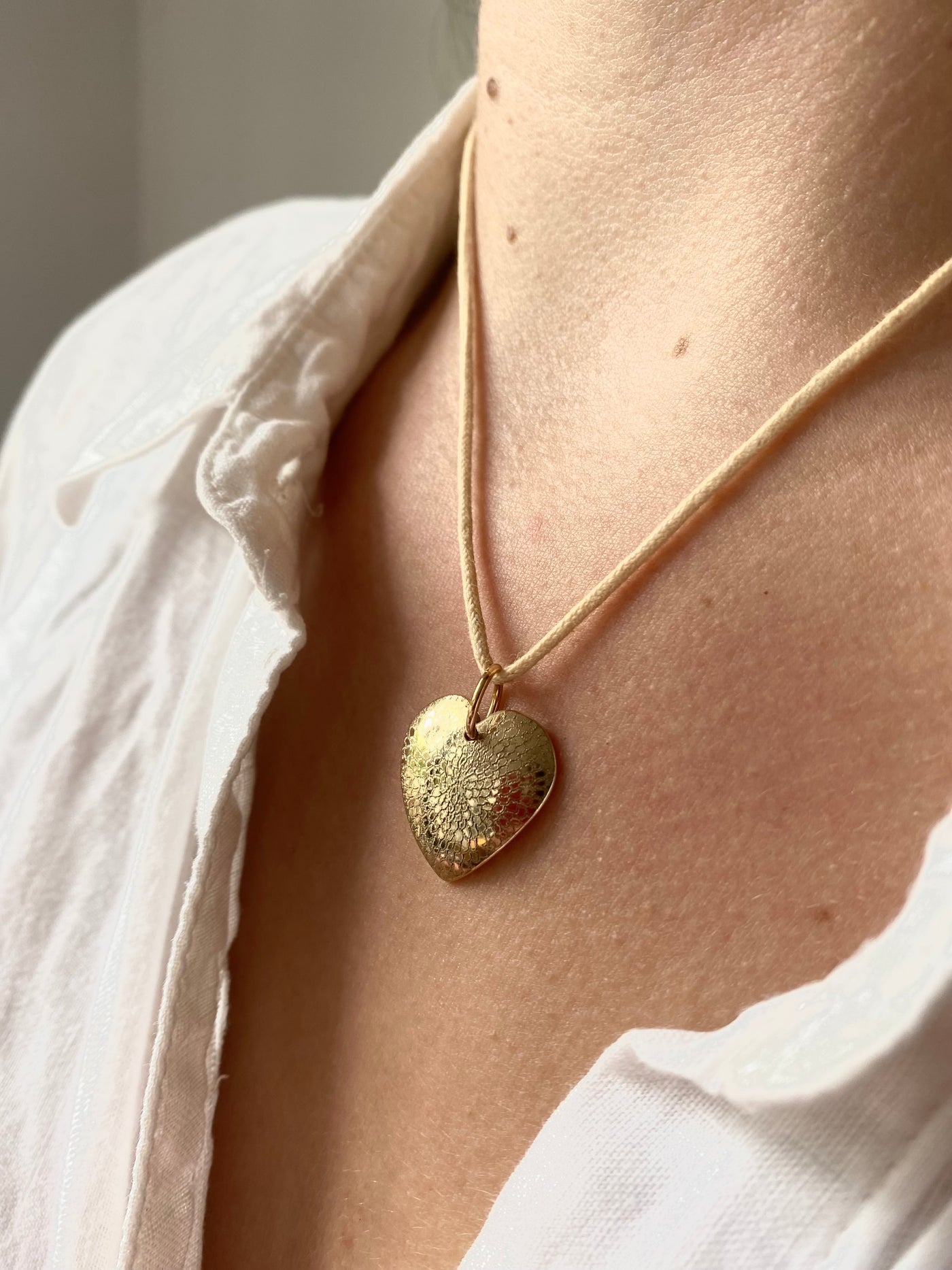 9ct yellow gold engraved pendant with a chrysanthemum design shown on a model wearing a white blouse. 