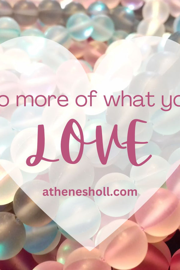 A heart-shaped graphic overlay with the quote 'Do more of what you LOVE' and the website athenesholl.com, set against a background of iridescent pastel beads in pink, blue, and white.