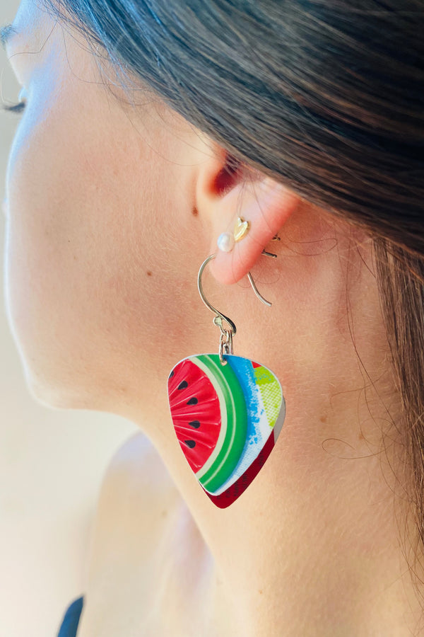 Close-up of a person wearing colorful watermelon slice earrings.