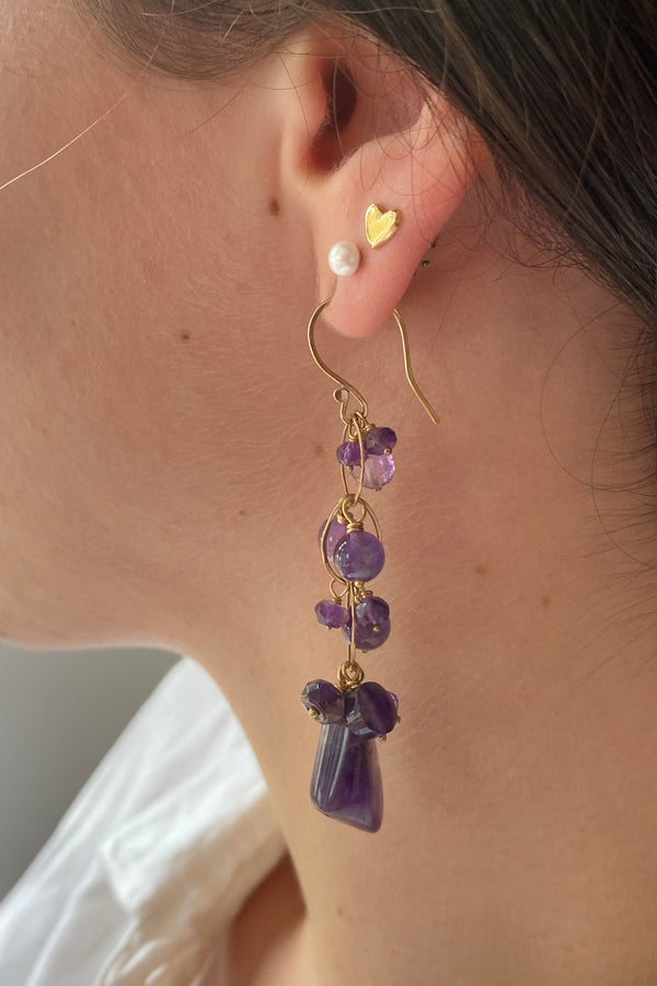 Close up of a model wearing a white blouse with an amethyst and gold waterfall earring