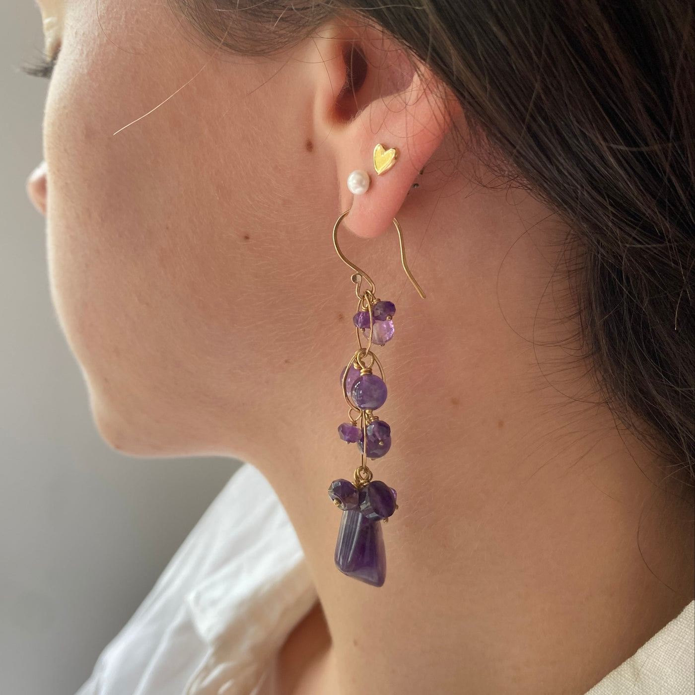 Close up of a model wearing a white blouse with an amethyst and gold waterfall earring