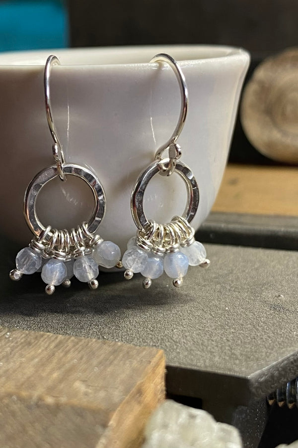 Silver hoop earrings with gemstones on a jewellers bench 