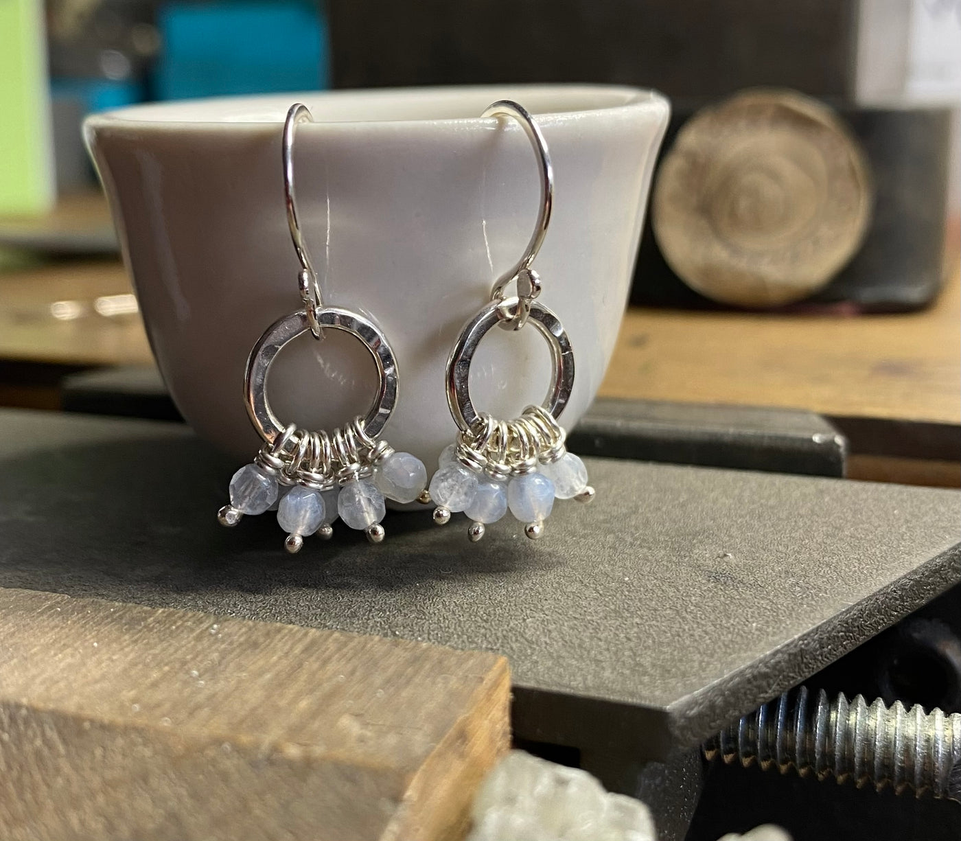 Silver hoop earrings with gemstones on a jewellers bench 