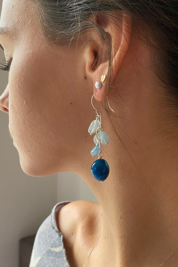 Close-up of a woman wearing colourful waterfall gemstone earrings in aquamarine and chalcedony