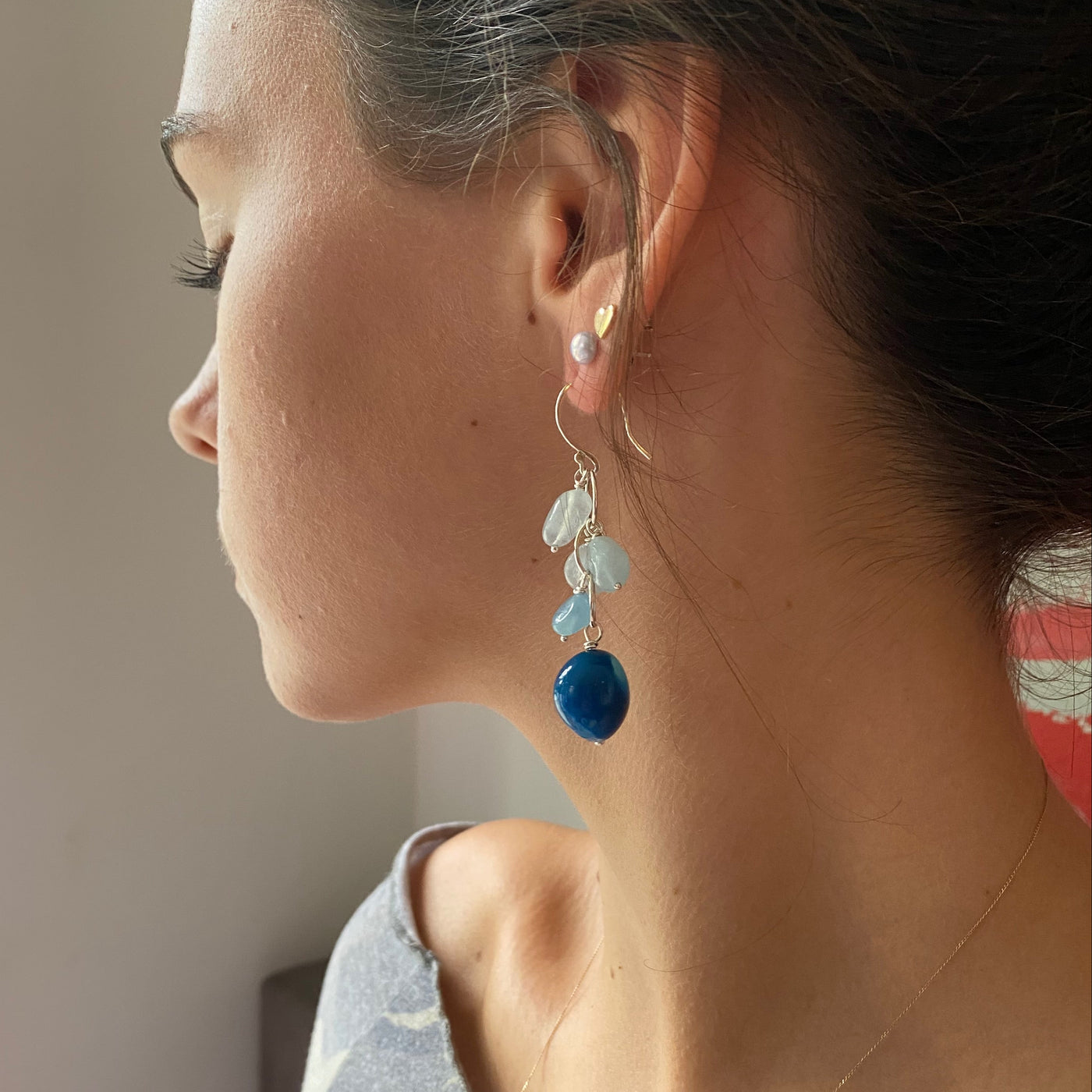 Close-up of a woman wearing colourful waterfall gemstone earrings in aquamarine and chalcedony