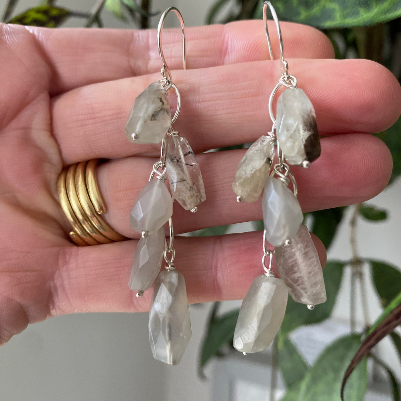 Beautiful waterfall earrings handmade in sterling silver, with luminous moonstone beads hanging from silver links. Displayed on the hand that made them. 