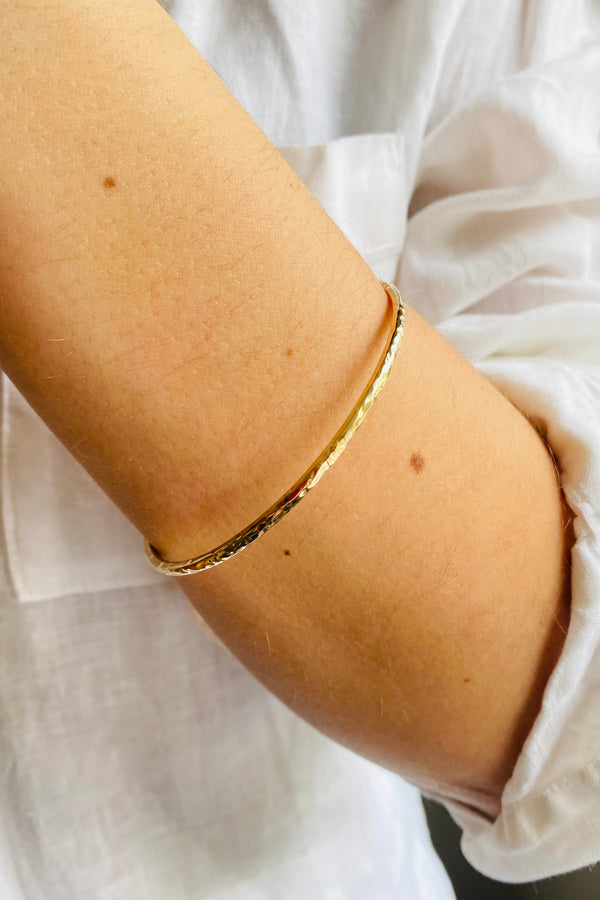 yellow gold hammer textured bangle worn on a wrist