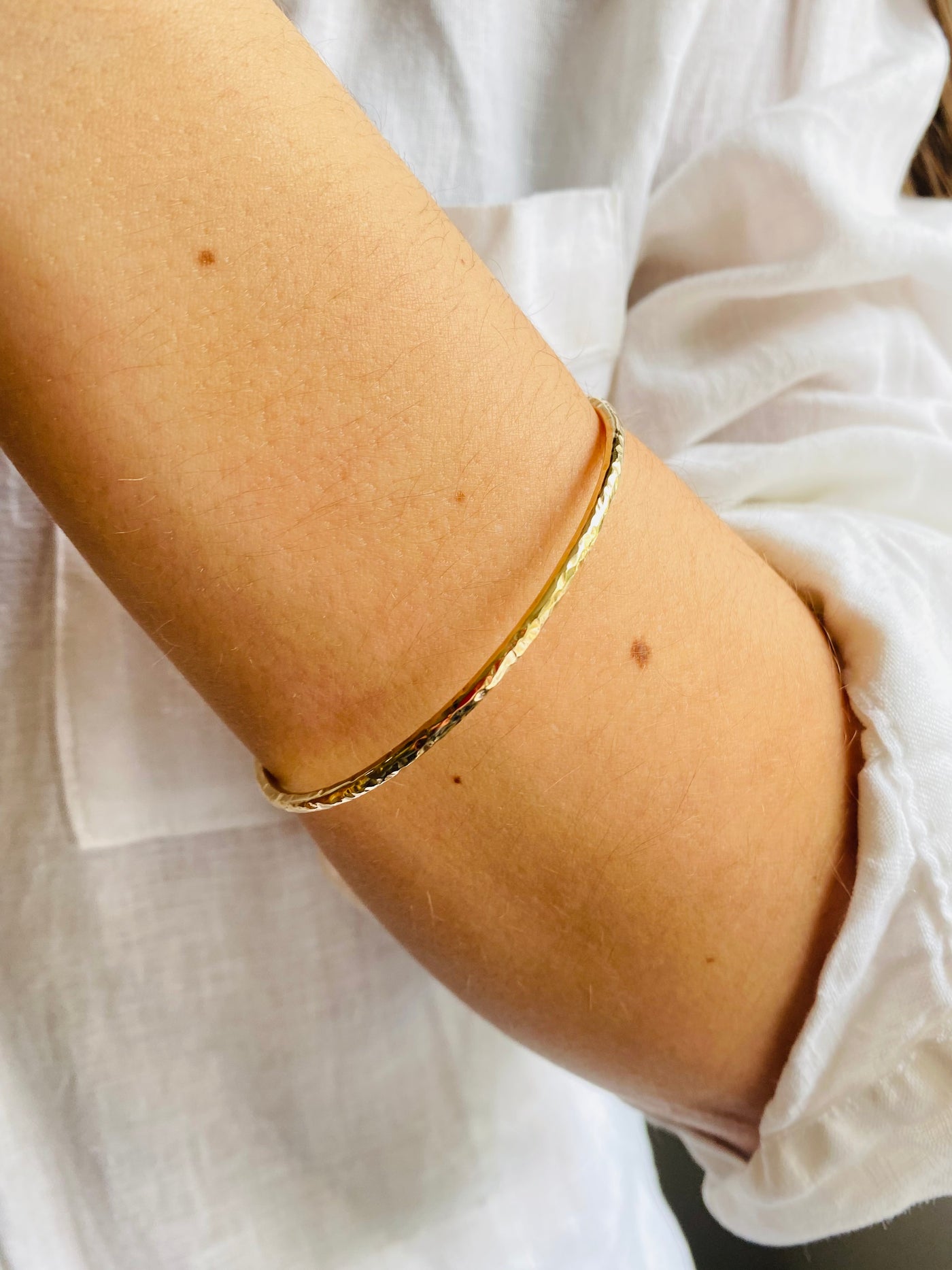 yellow gold hammer textured bangle worn on a wrist