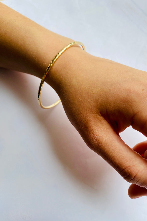 yellow gold textured bangle on a wrist