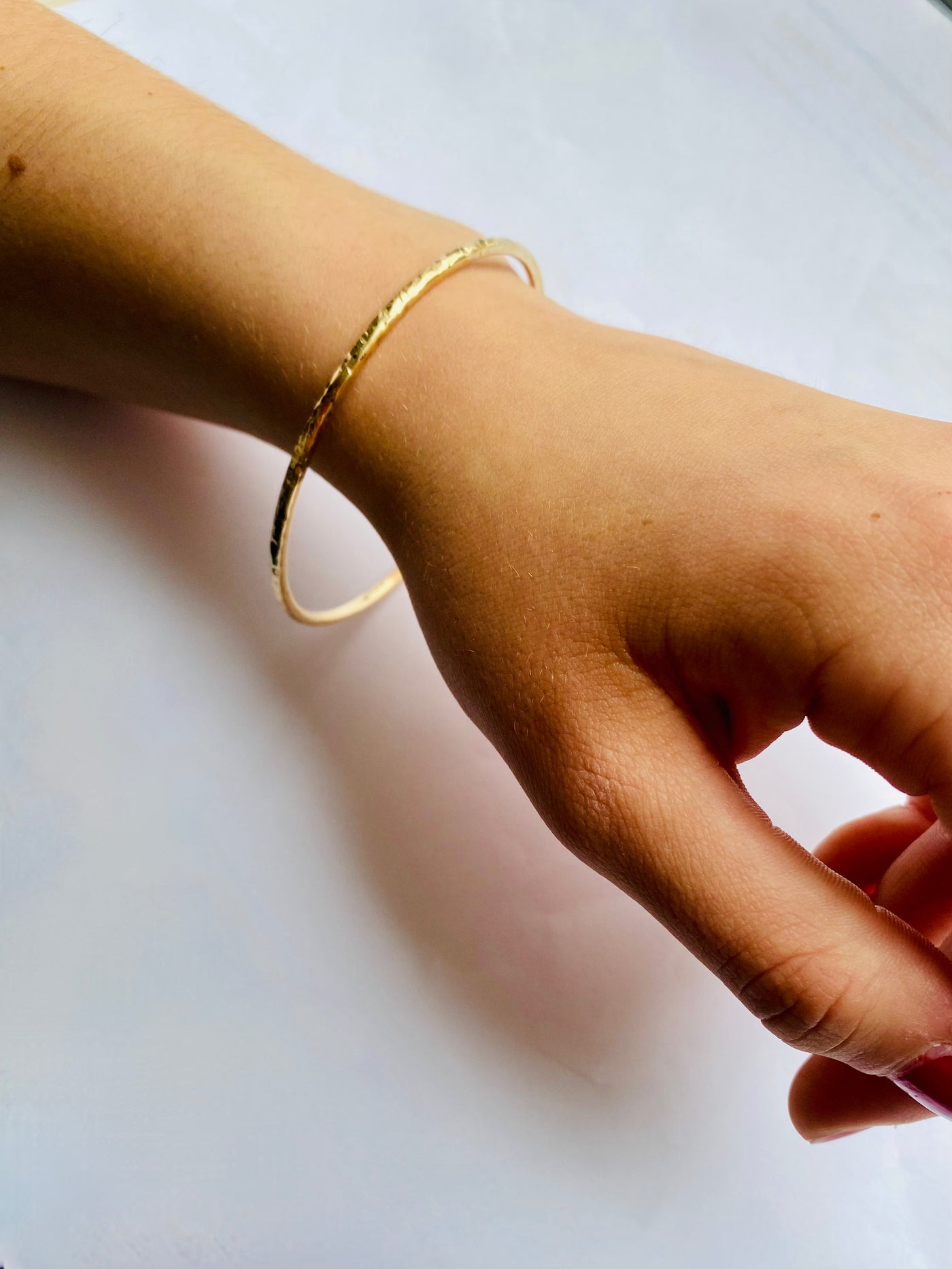 yellow gold textured bangle on a wrist