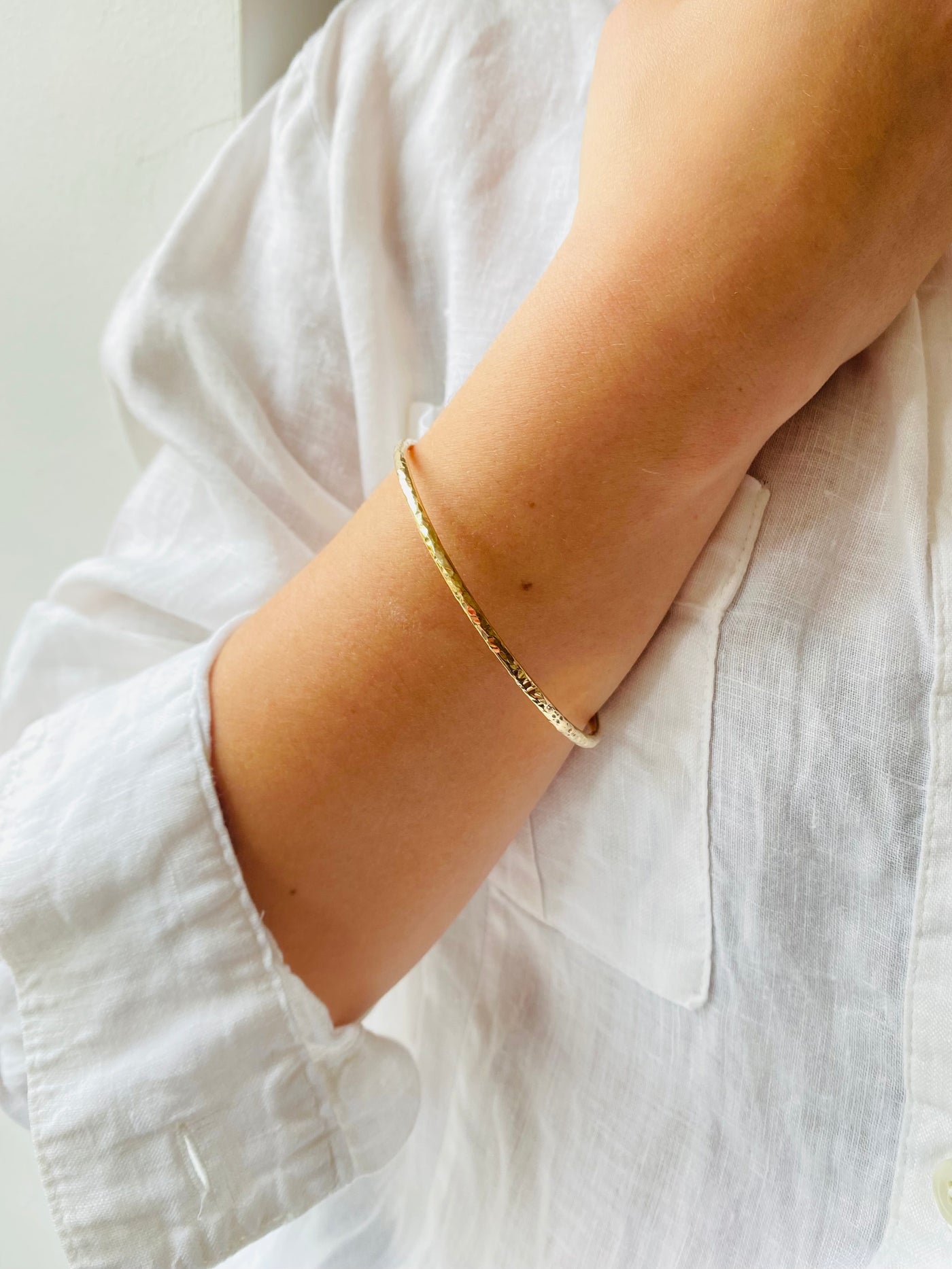 yellow gold textured bangle on a model wearing a white blouse