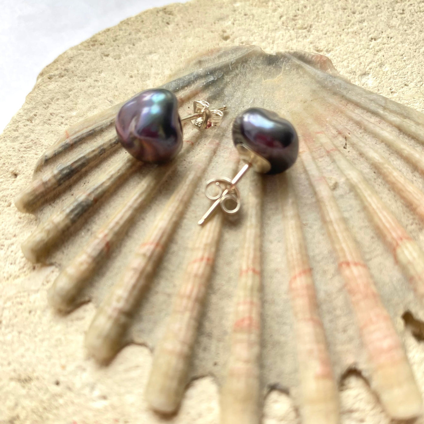 Pair of black pearl earrings on a shell