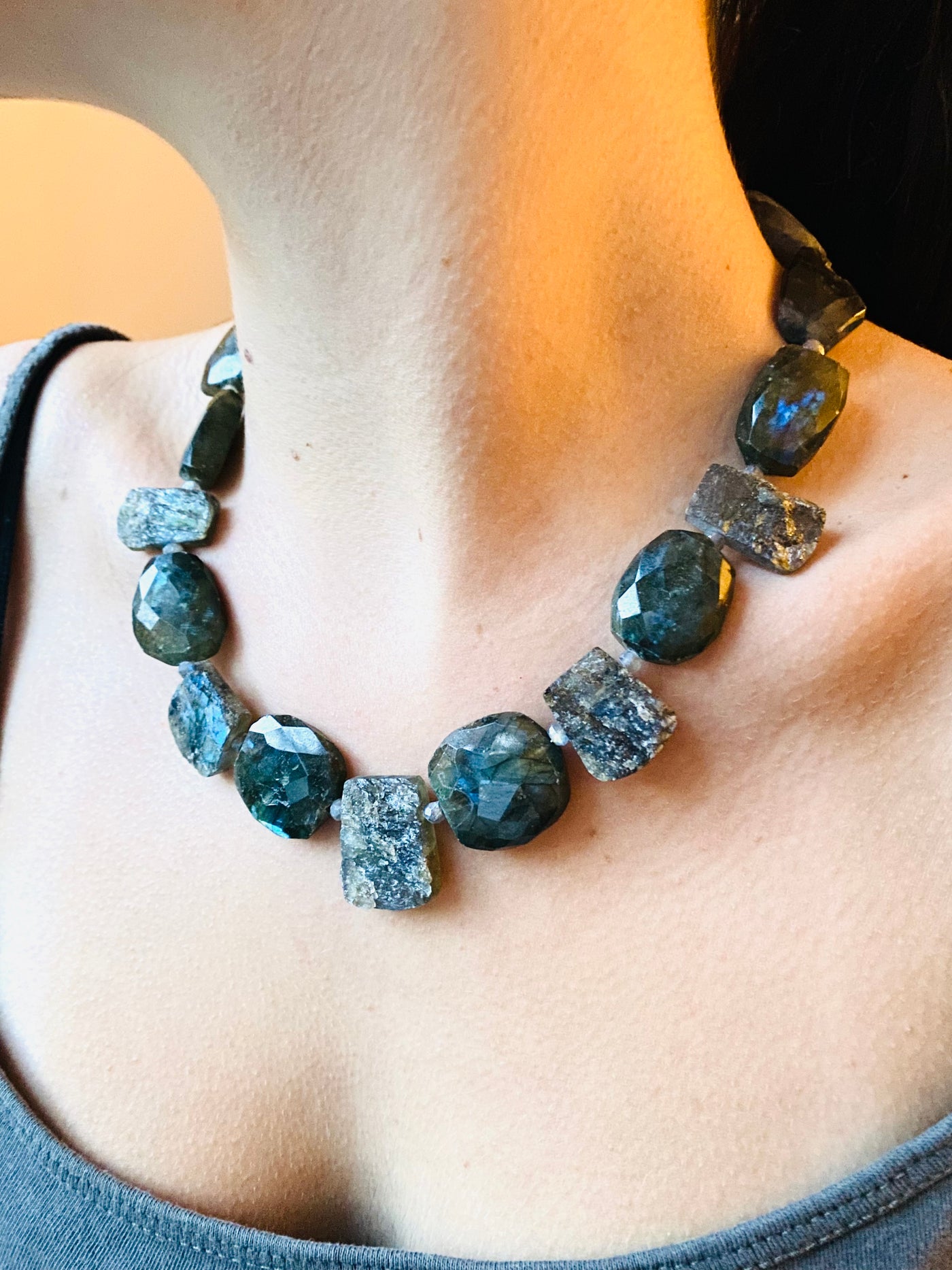 Necklace in labradorite gemstone slabs and faceted beads, worn by a model. 