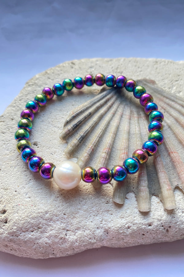 Rinbow coloured hematite bead bracelet on a stone background