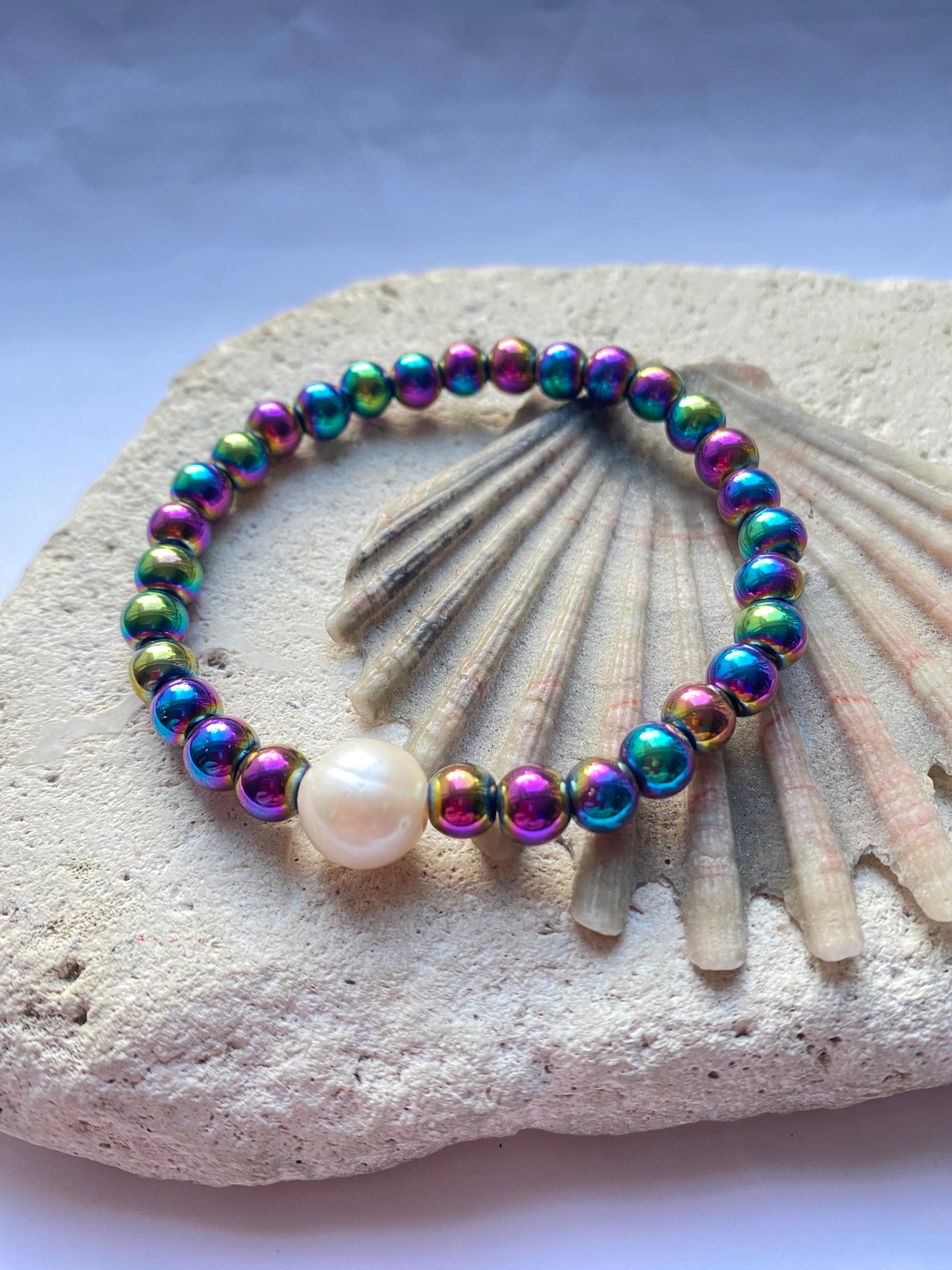 Rinbow coloured hematite bead bracelet on a stone background