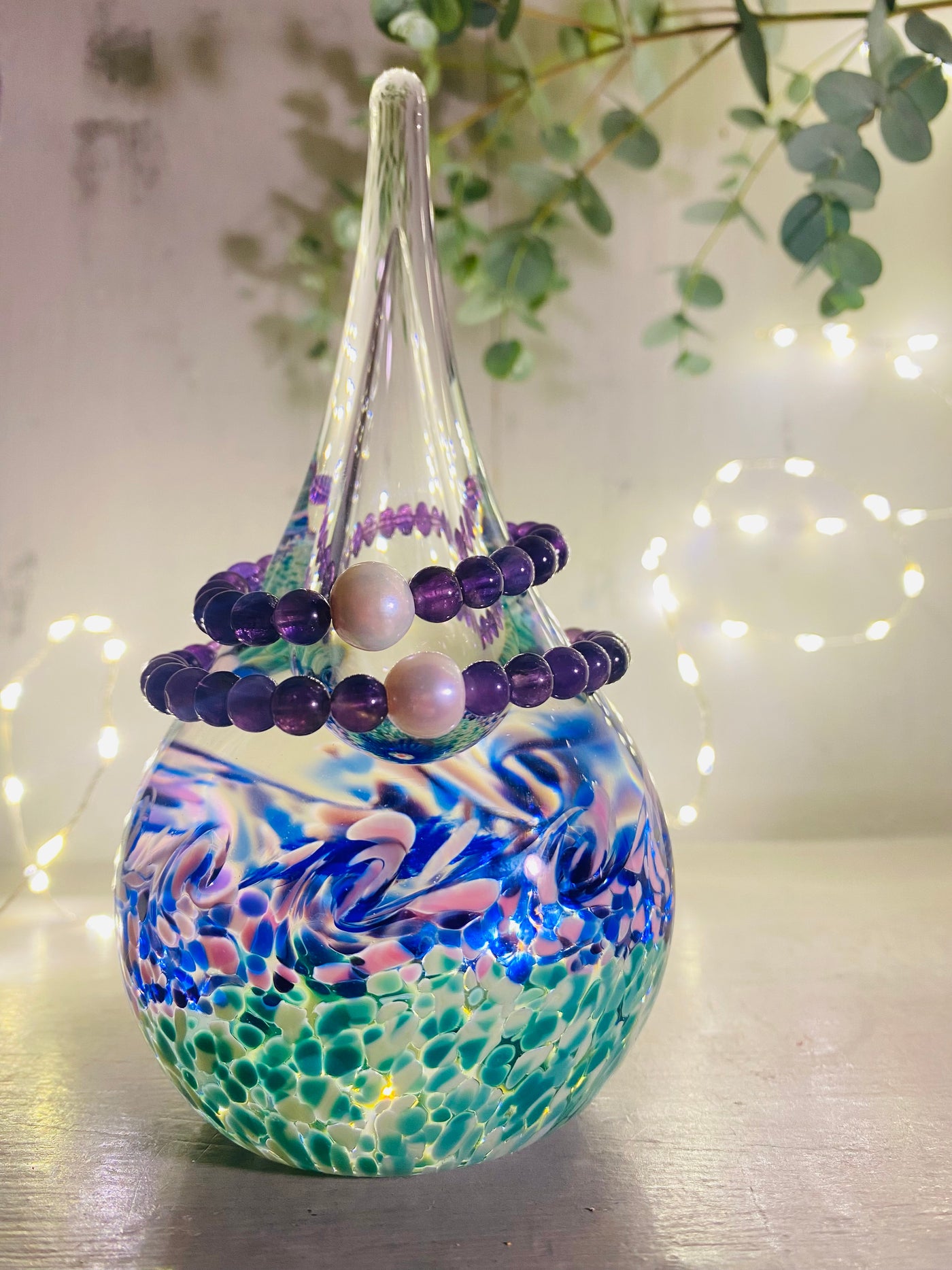 purple amethust bracelets displayed on a glass stand with fairy lights in the background