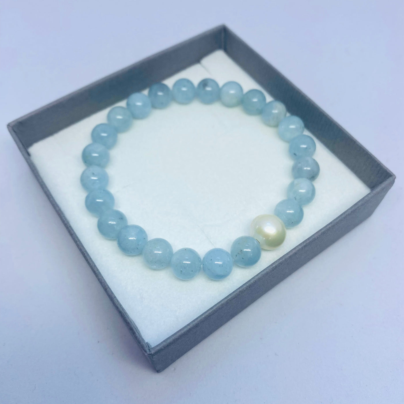 Beaded aquamarine gemstone bracelet with a freshwater pearl in a gift box on a light background