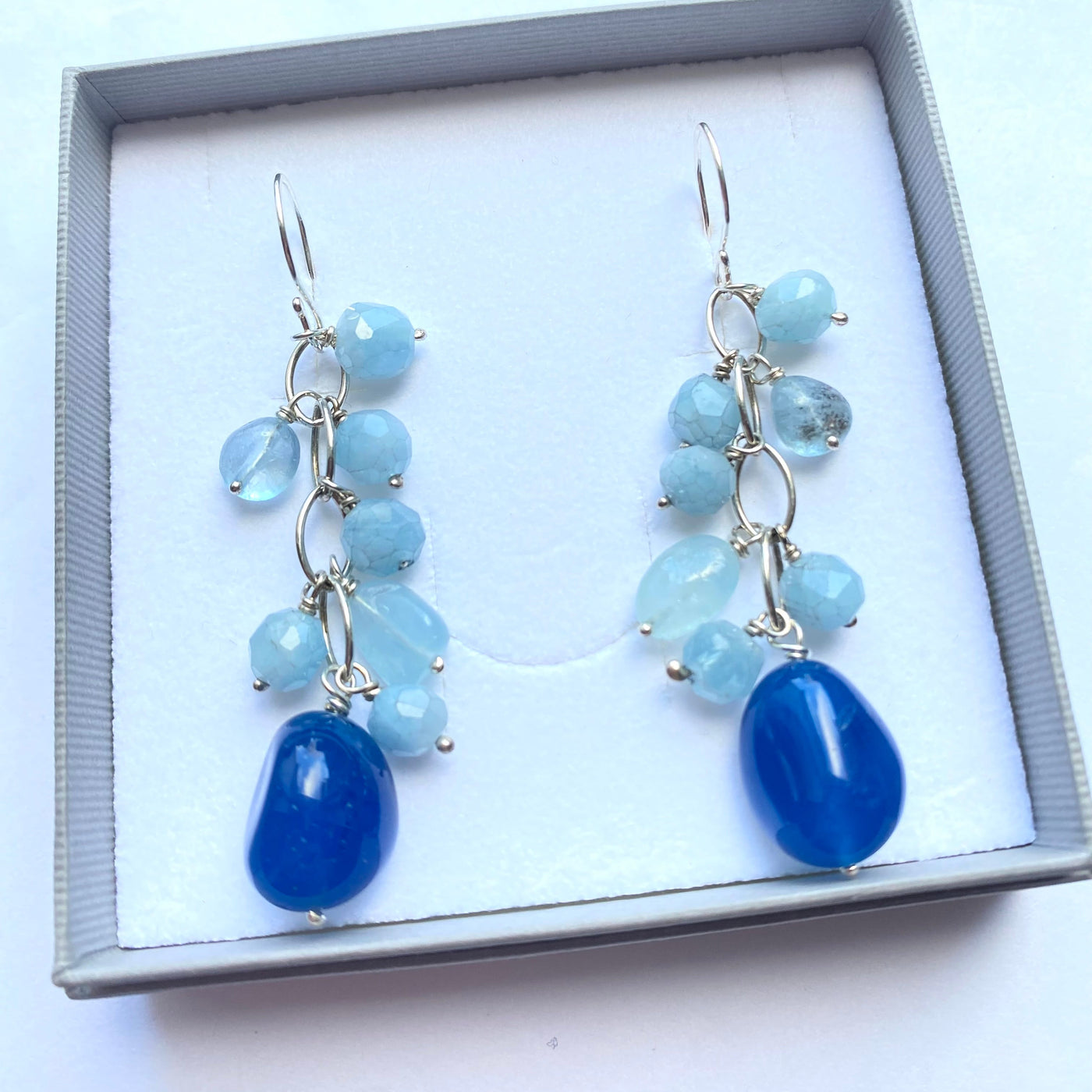 Deep blue chalcedony and pale blue aquamarine beaded gemstone earrings in a  gift box on a white background