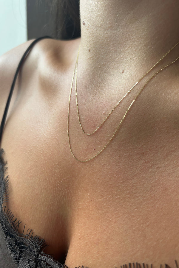 Close up of a model wearing 2 lengths of chain to illustrate how they sit on the body. 