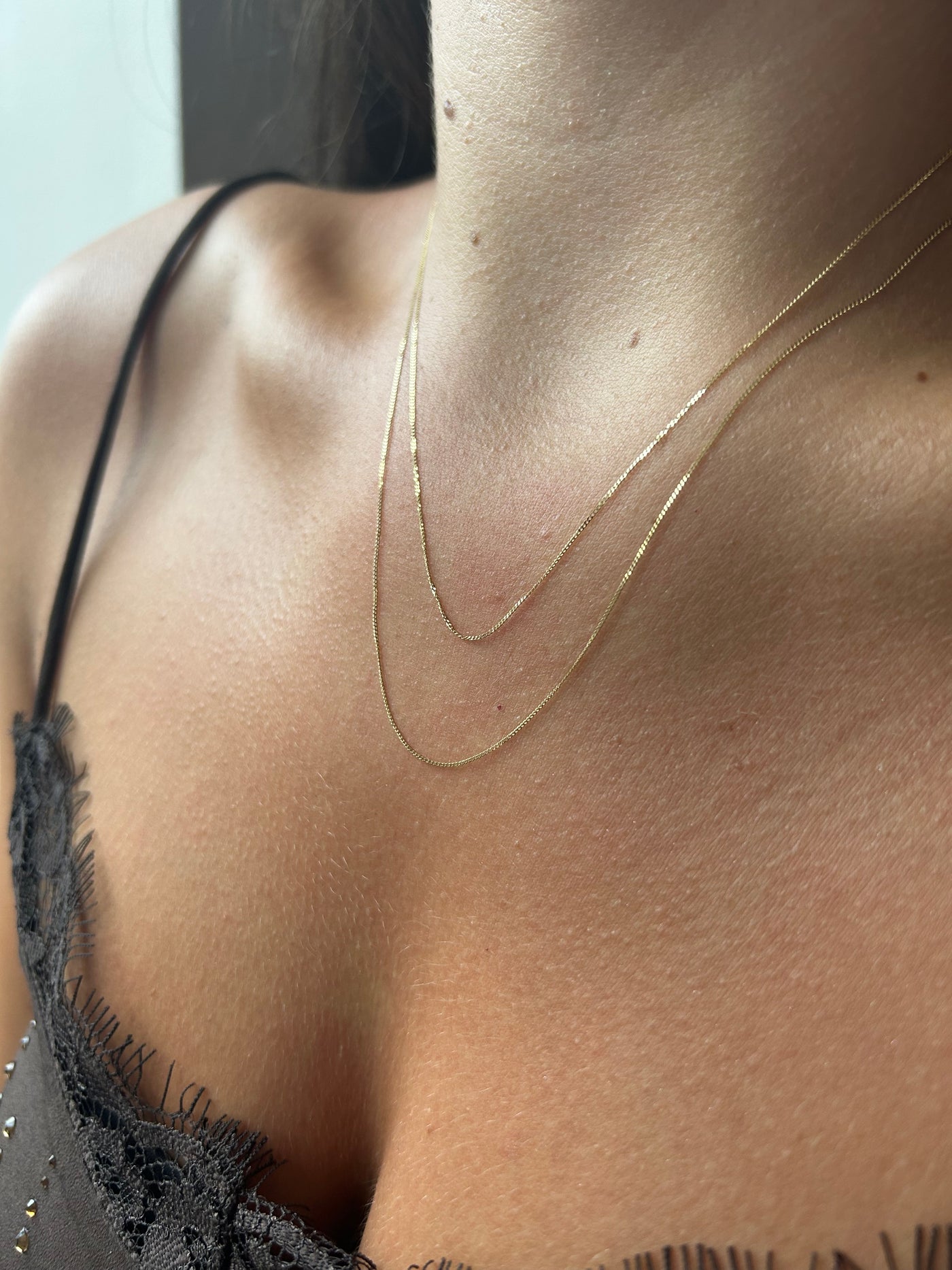 Close up of a model wearing 2 lengths of chain to illustrate how they sit on the body. 