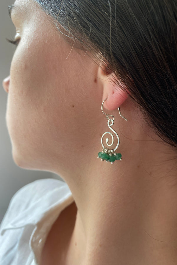 Spiral emerald ruffle earrings woen by a model with dark hair
