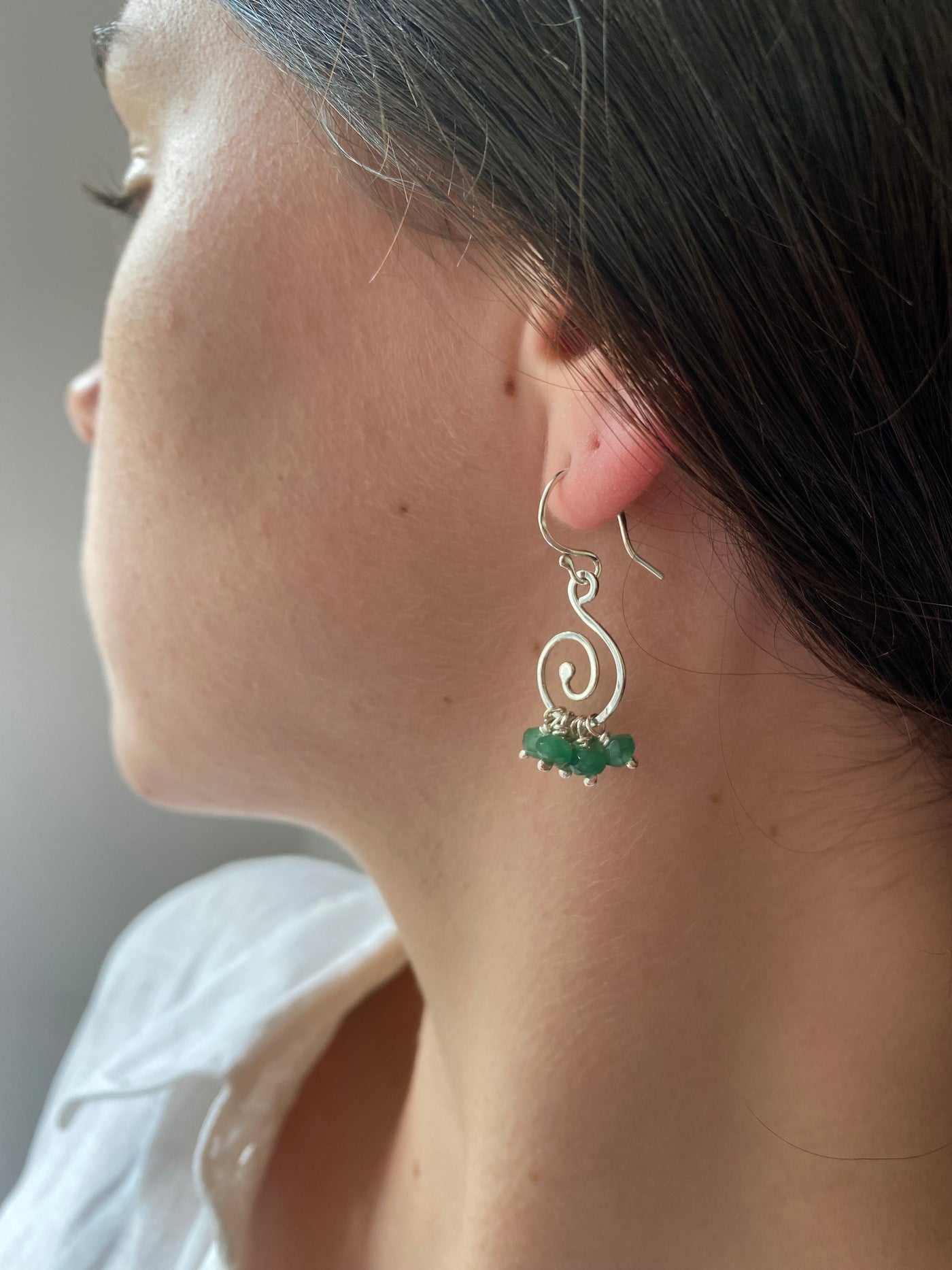 Spiral emerald ruffle earrings woen by a model with dark hair