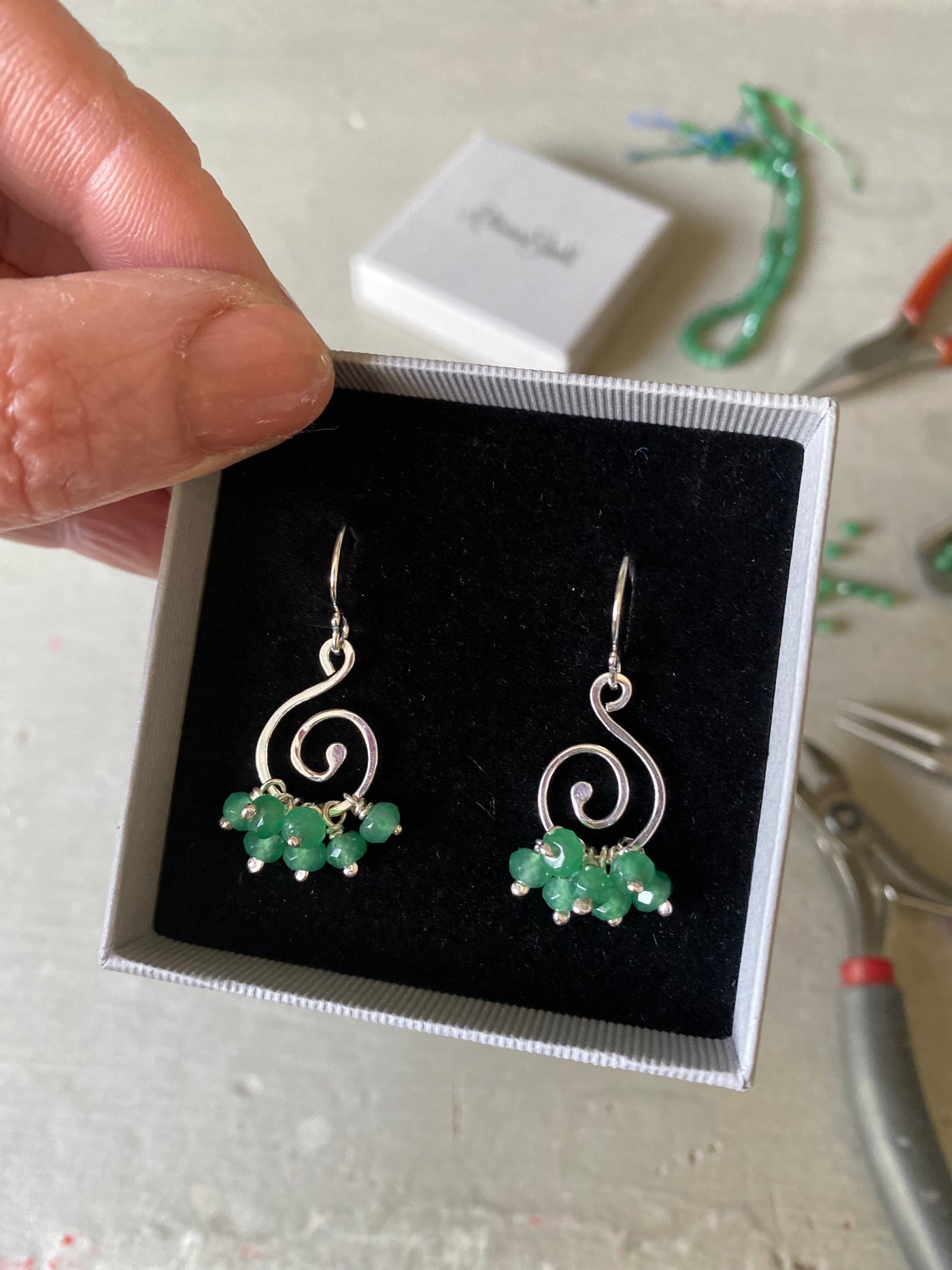 Emerald and silver spiral earrings displayed in a black velvet lined gift box