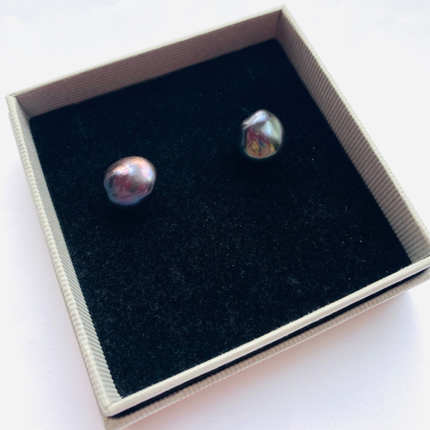 Pair of peacock blue baroque pearl earrings in a gift box on a white background