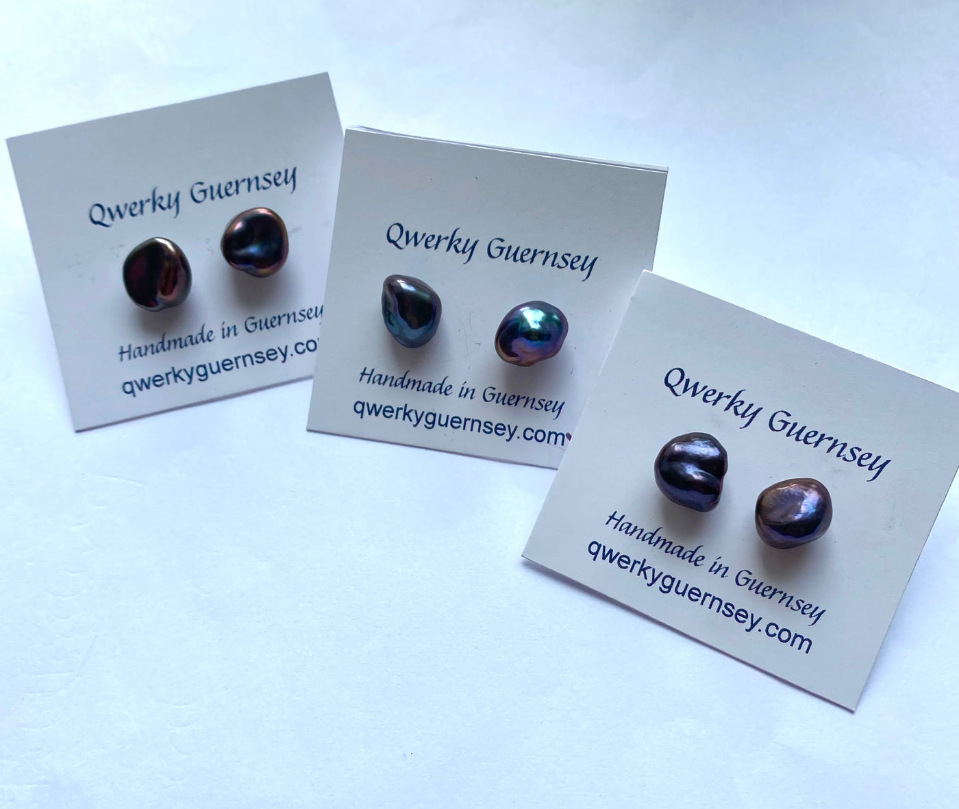 Three pairs of earrings on Qwerky Guernsey branded cards against a white background
