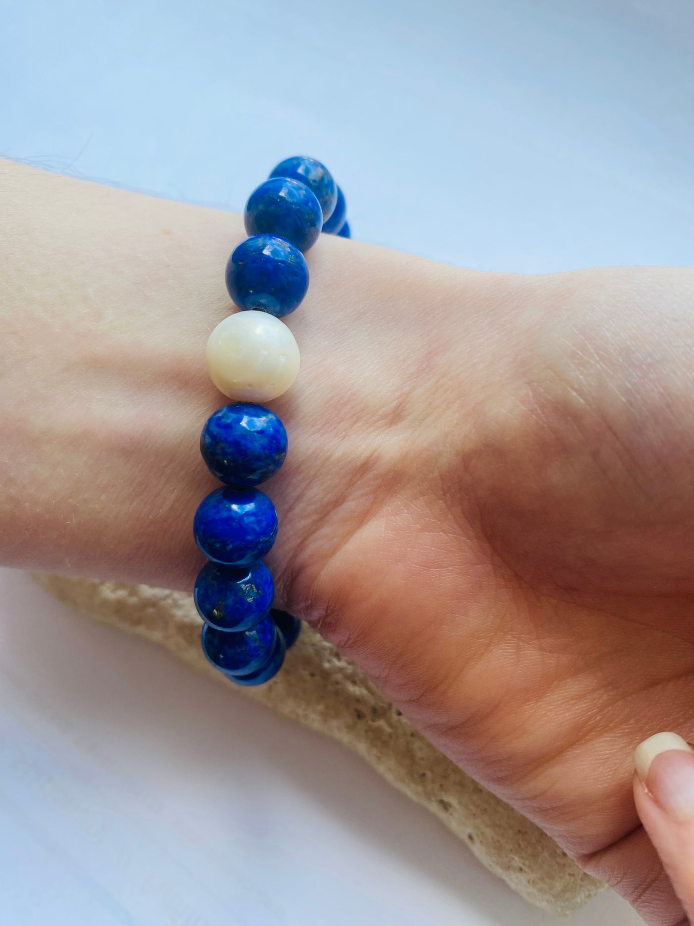 Blue and white beaded bracelet on a wrist with a light background