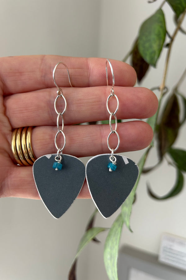 earrings in silver and recycled plastic, cut into plectrum shapes, displayed on a hand