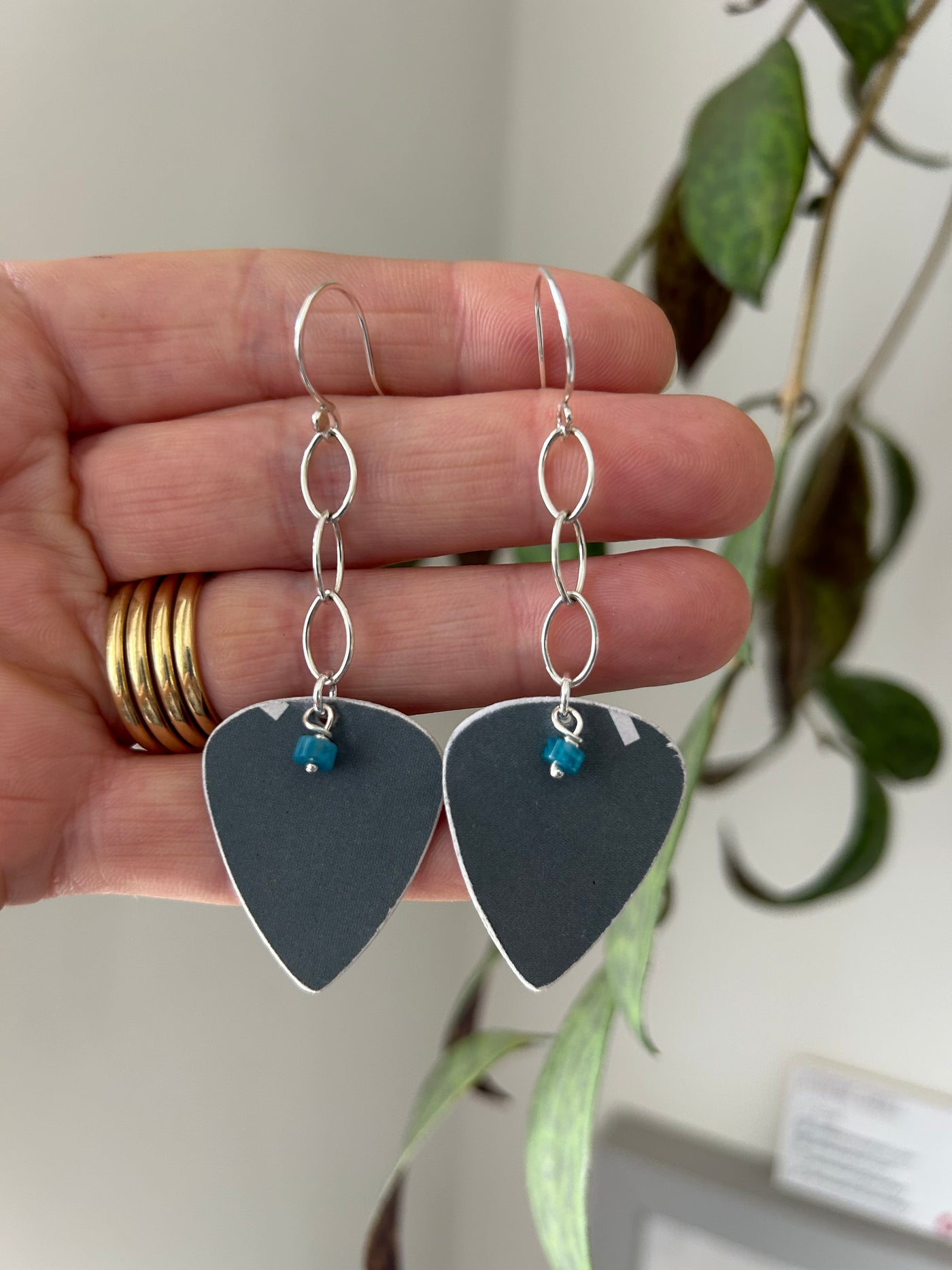 earrings in silver and recycled plastic, cut into plectrum shapes, displayed on a hand