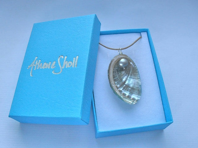 Necklace with a shell pendant in a blue box labeled 'Athene Sholl'.