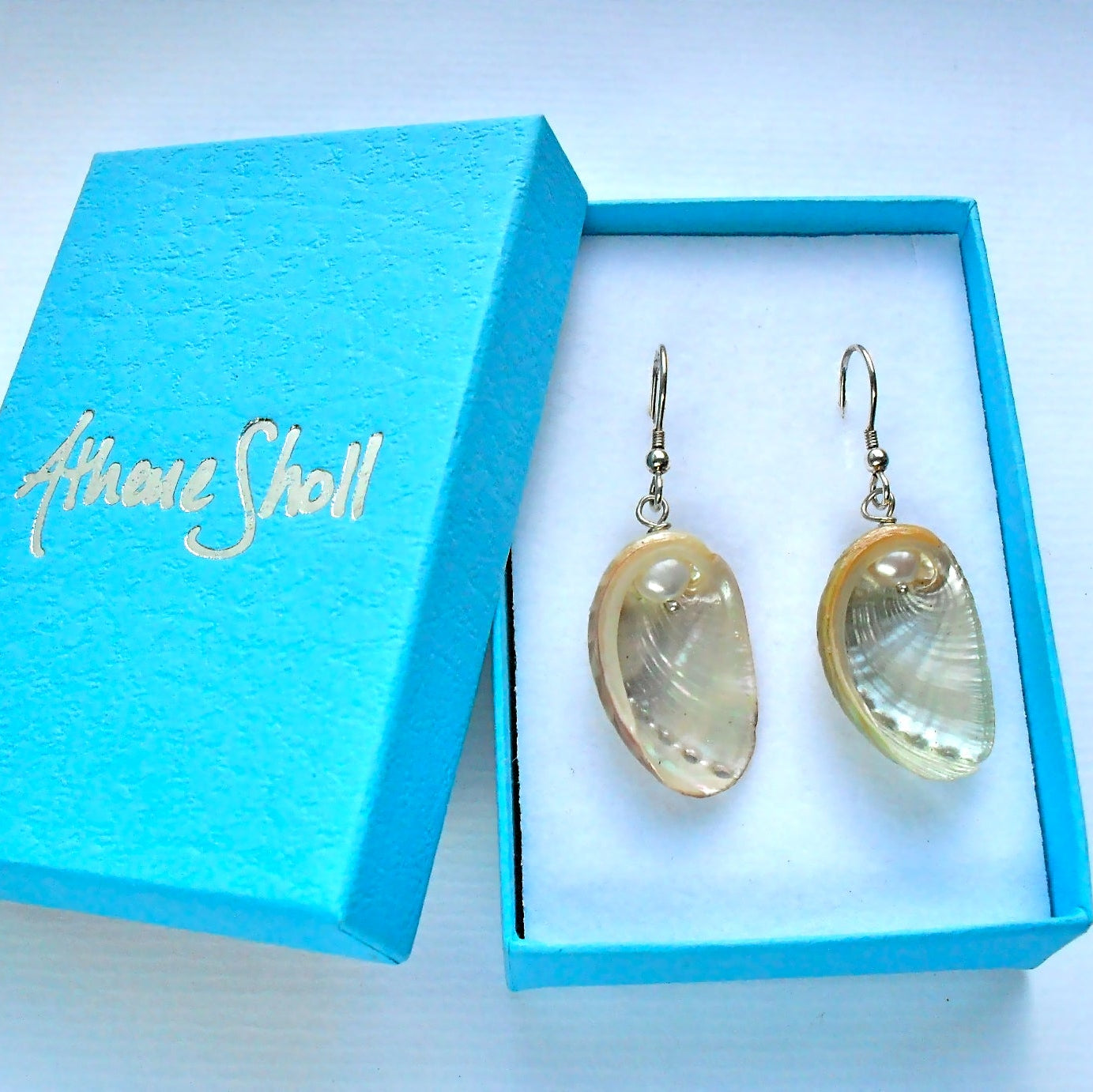 Guernsey natural ormer shell earrings with white freshwater pearl accents, displayed in a gift box