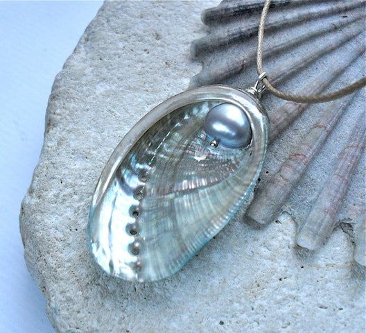 Shell pendant with a pearl on a rock