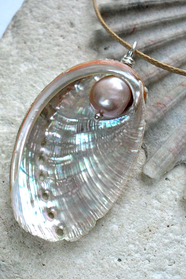 Shell pendant with pearl on a stone surface
