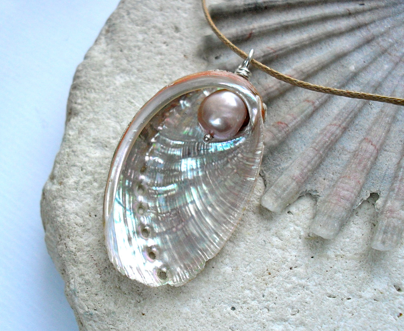Shell pendant with pearl on a stone surface