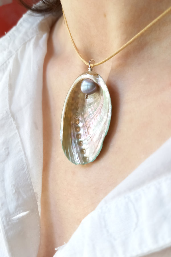 Close-up of a necklace with a shell pendant on a white background