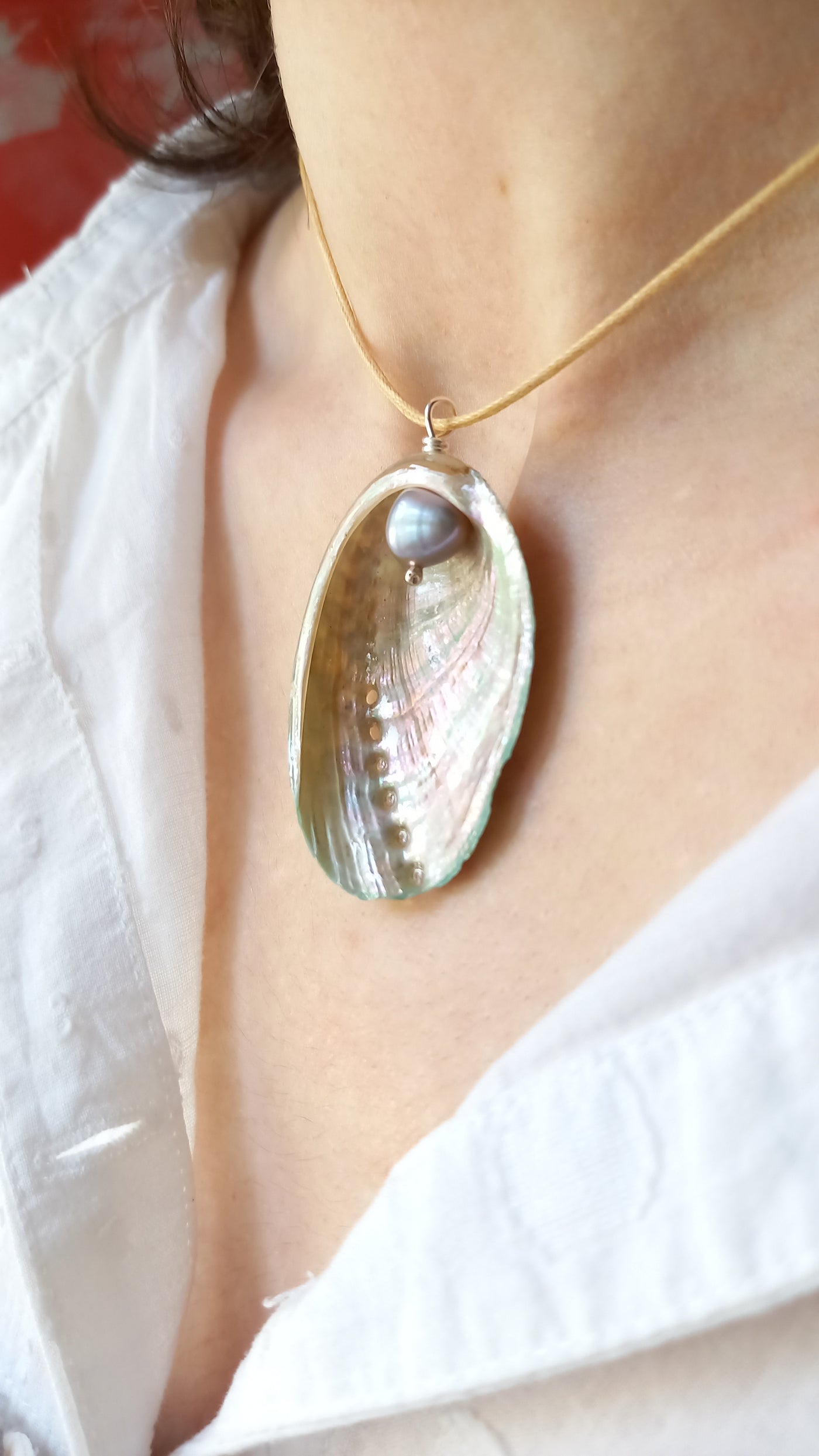 Close-up of a necklace with a shell pendant on a white background