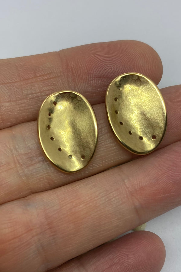 Guernsey ormer shell earrings in textured 9ct yellow gold, held on a hand