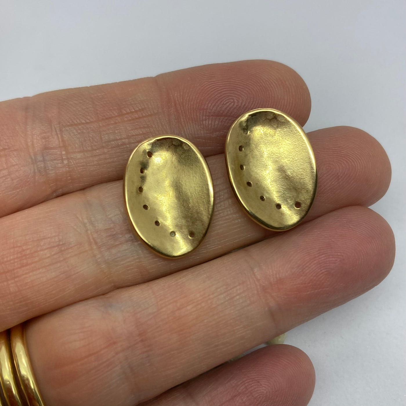 Guernsey ormer shell earrings in textured 9ct yellow gold, held on a hand