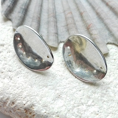 Pair of textured silver ormer stud earrings on a shell background