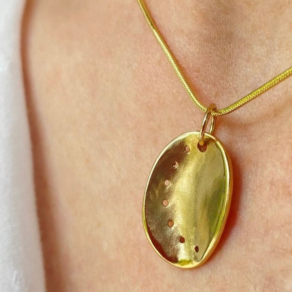 Guernsey ormer pendant in 9ct yellow gold on a gold snake chain, worn on a model