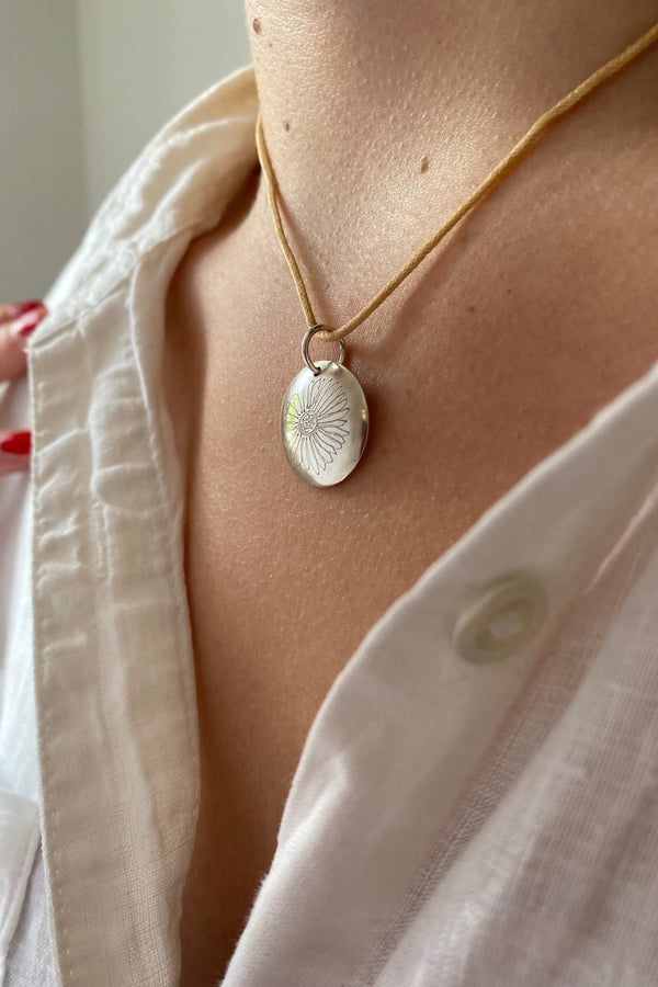 Close-up of a person wearing a white shirt  and a St Peter Port Daisy pendant necklace