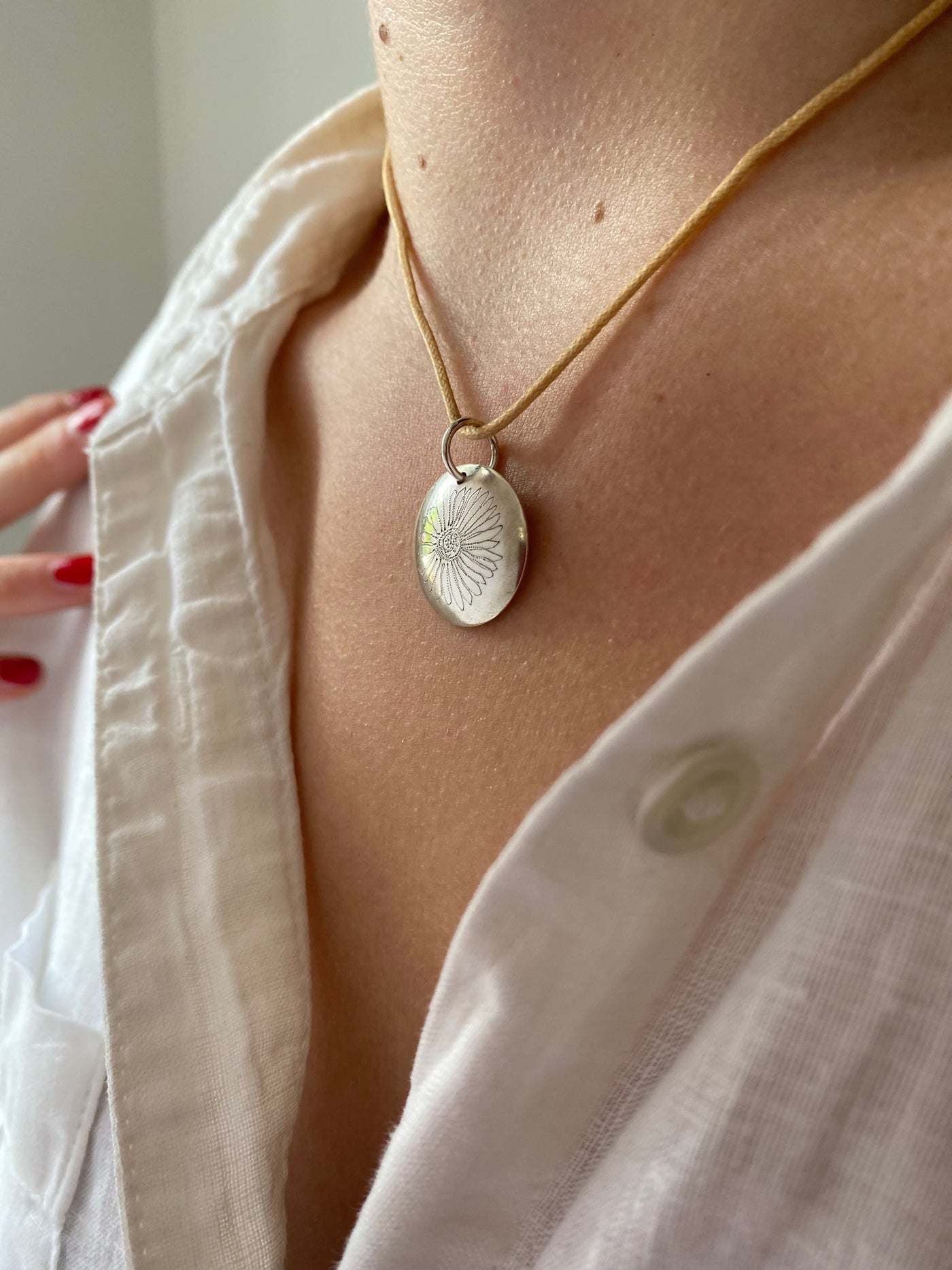 Close-up of a person wearing a white shirt  and a St Peter Port Daisy pendant necklace