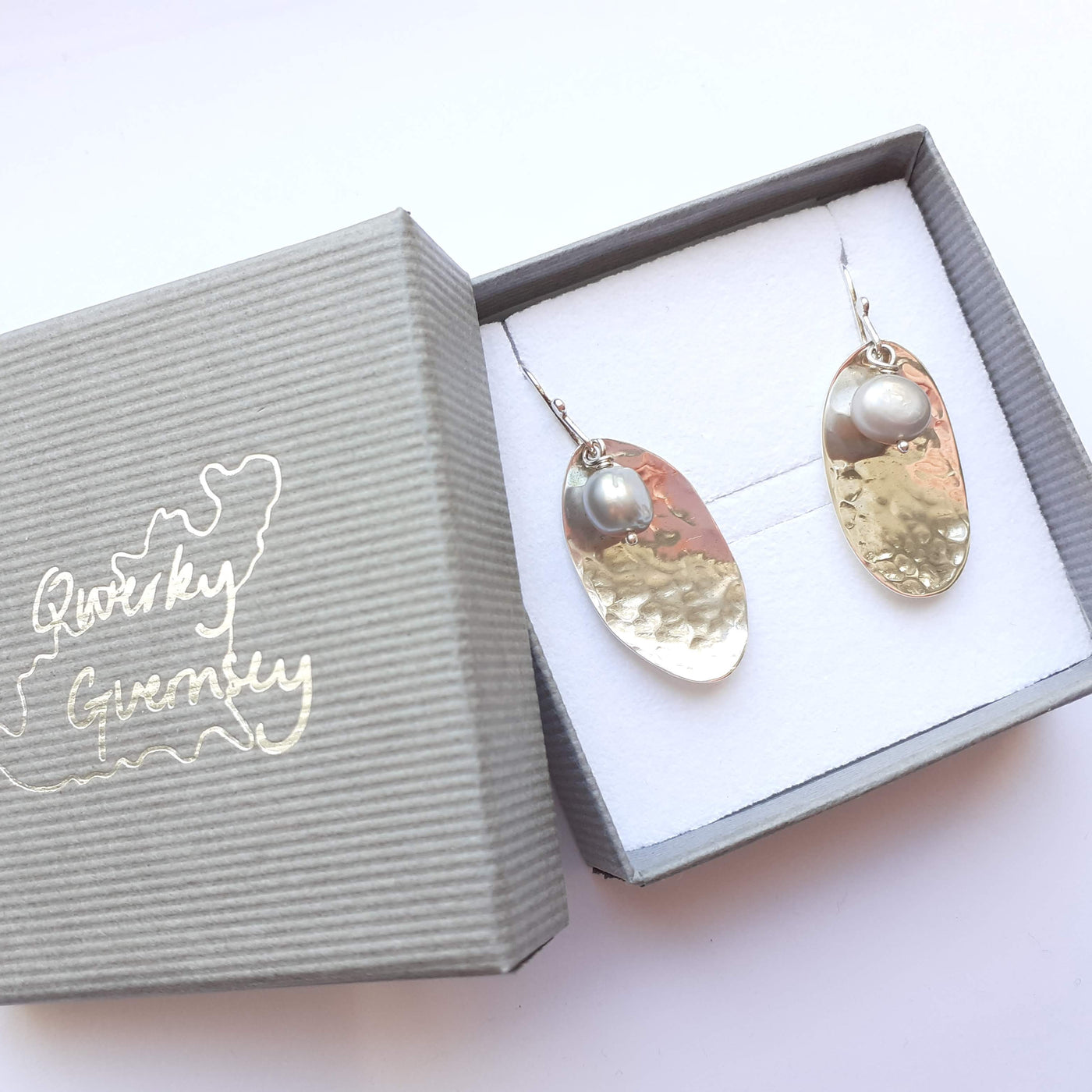 Guernsey potato peel pie earrings in silver with grey freshwater pearl accents, displayed in a gift box. 