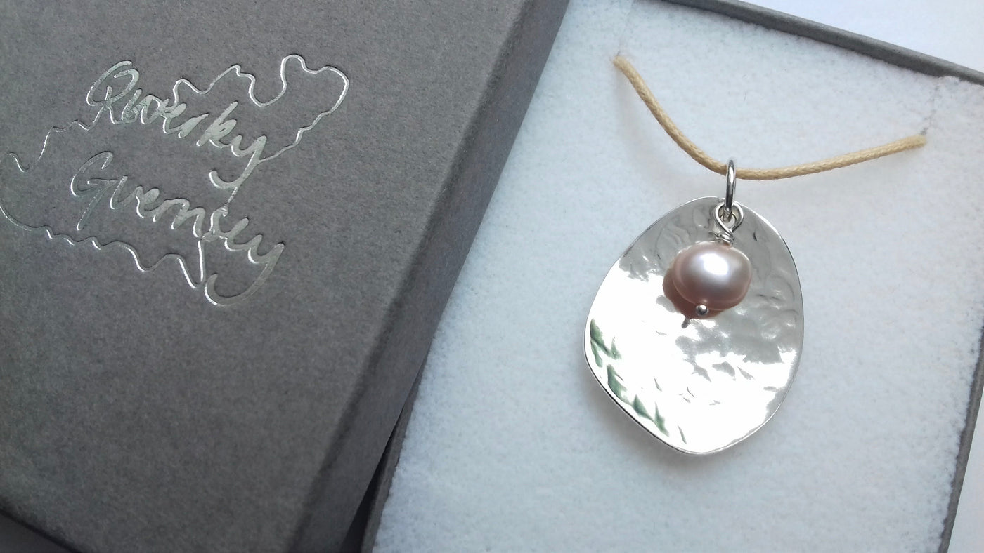 Silver pendant necklace with a pearl on a gray background