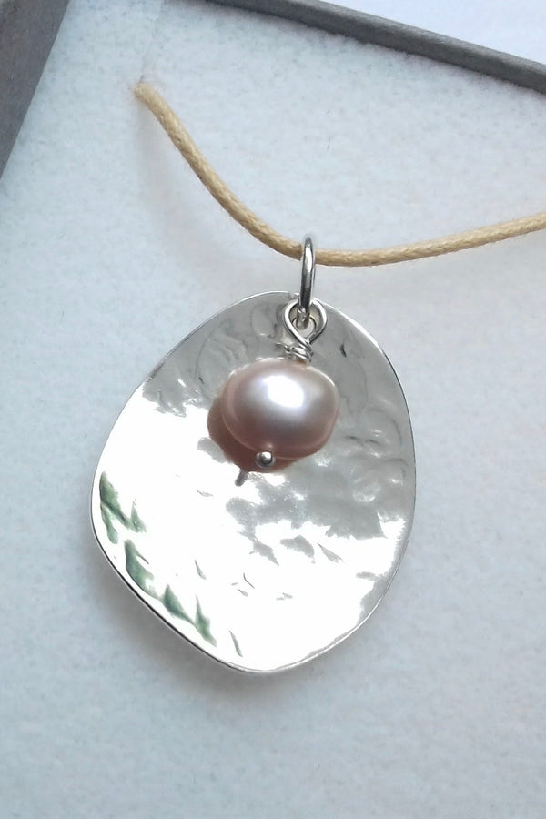 Silver potato peel pendant necklace with a pink pearl on a gray background